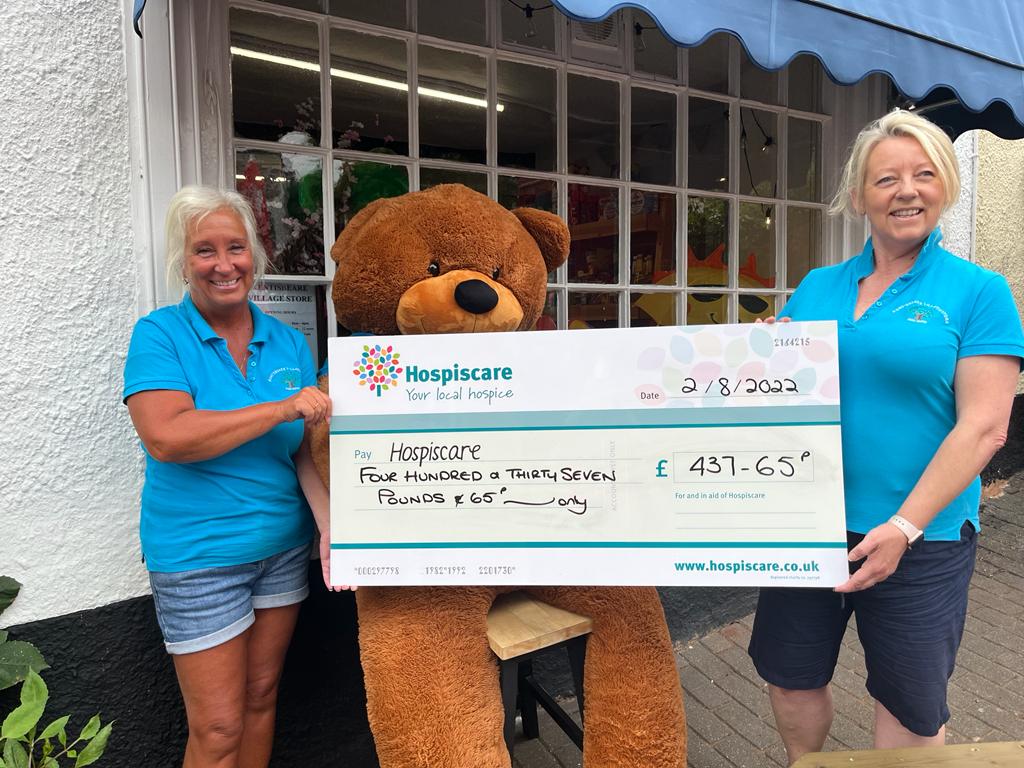 Two women holding a big cheque in front of a giant teddy