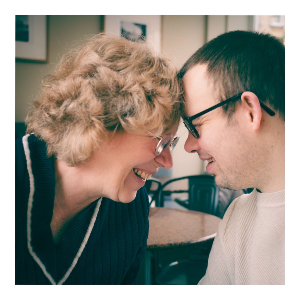 A woman and man laughing with their foreheads pressed together