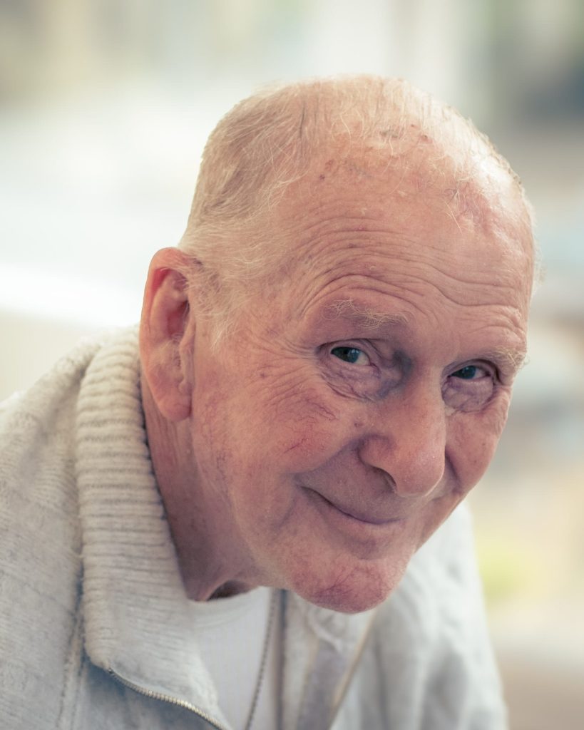 A close-up of an older man smiling at the camera