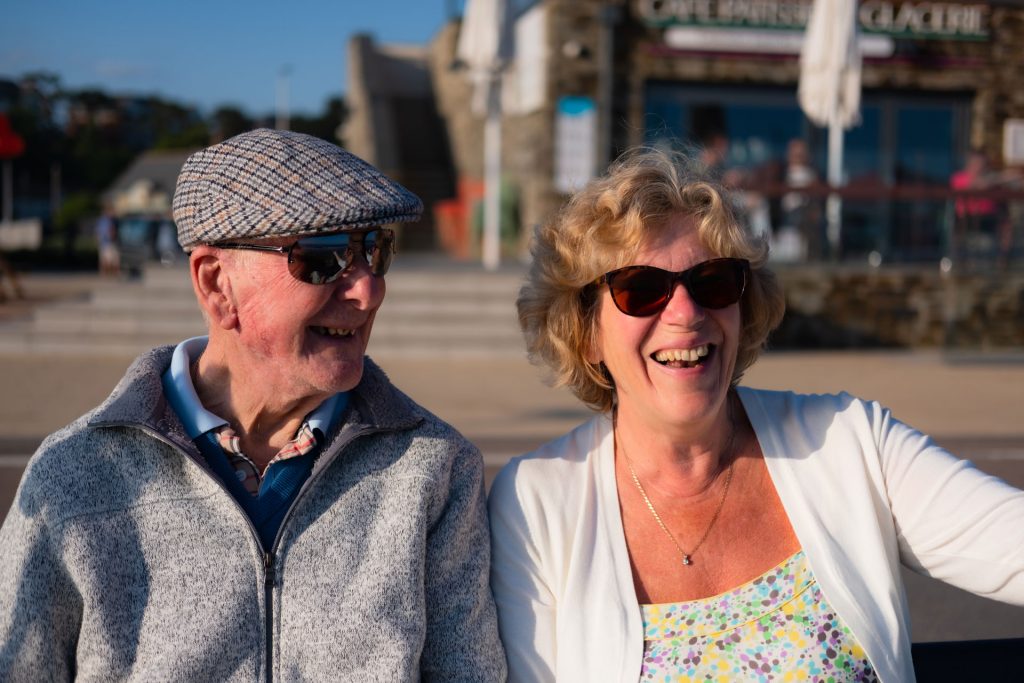 A man and woman outside laughing wearing sunglasses