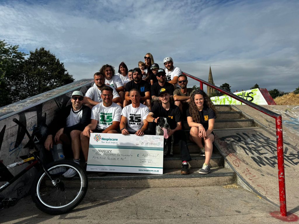 A group of BMX'ers holding a giant cheque in a skate park