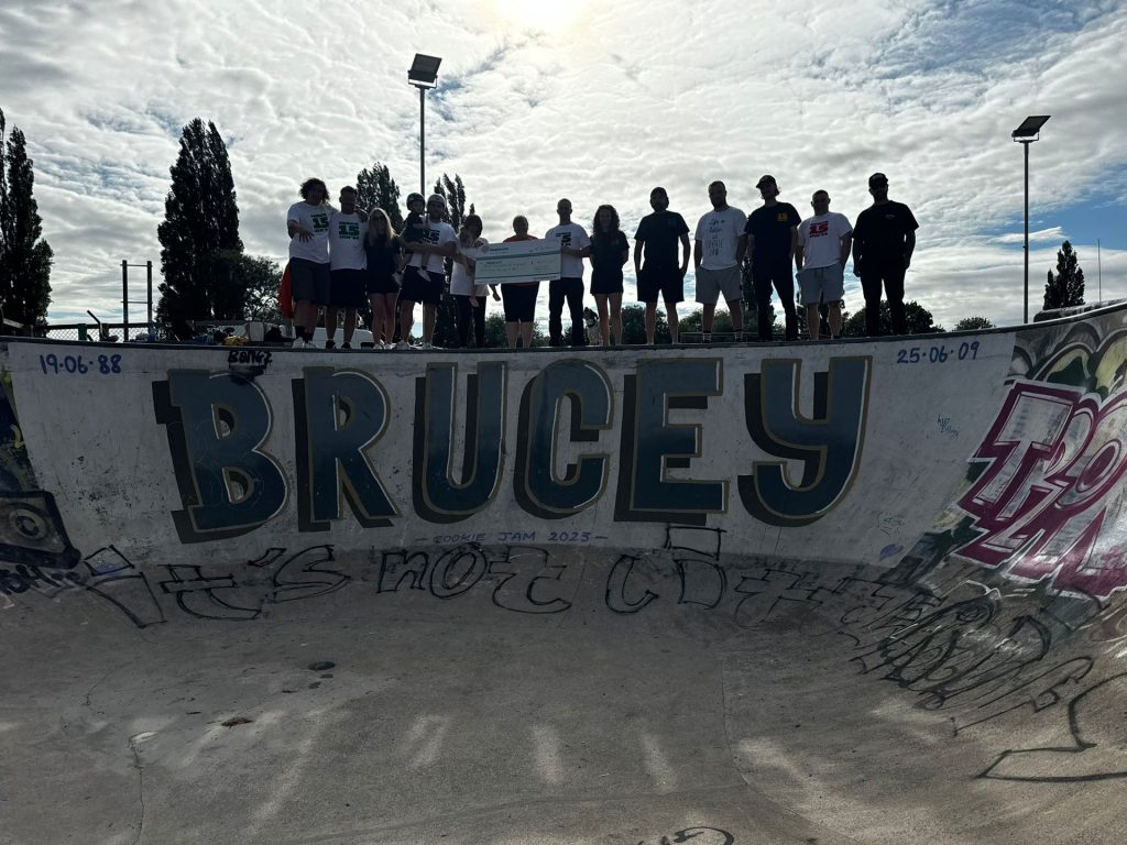 Graffiti reading 'Brucey' in a skate park with people gathered around it