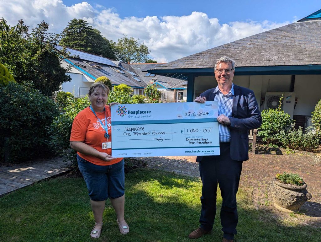 A man and woman holding a giant cheque in a garden