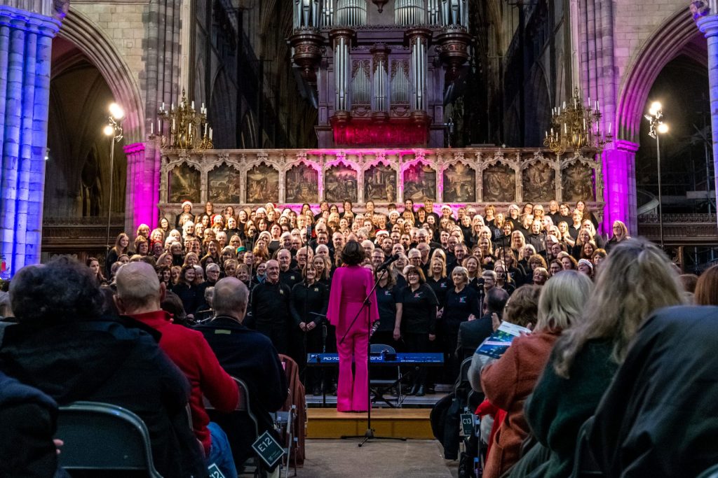 A large group choir singing in Exeter Cathedral