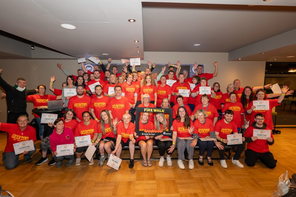 A group of people in orange t-shirts holding certificates