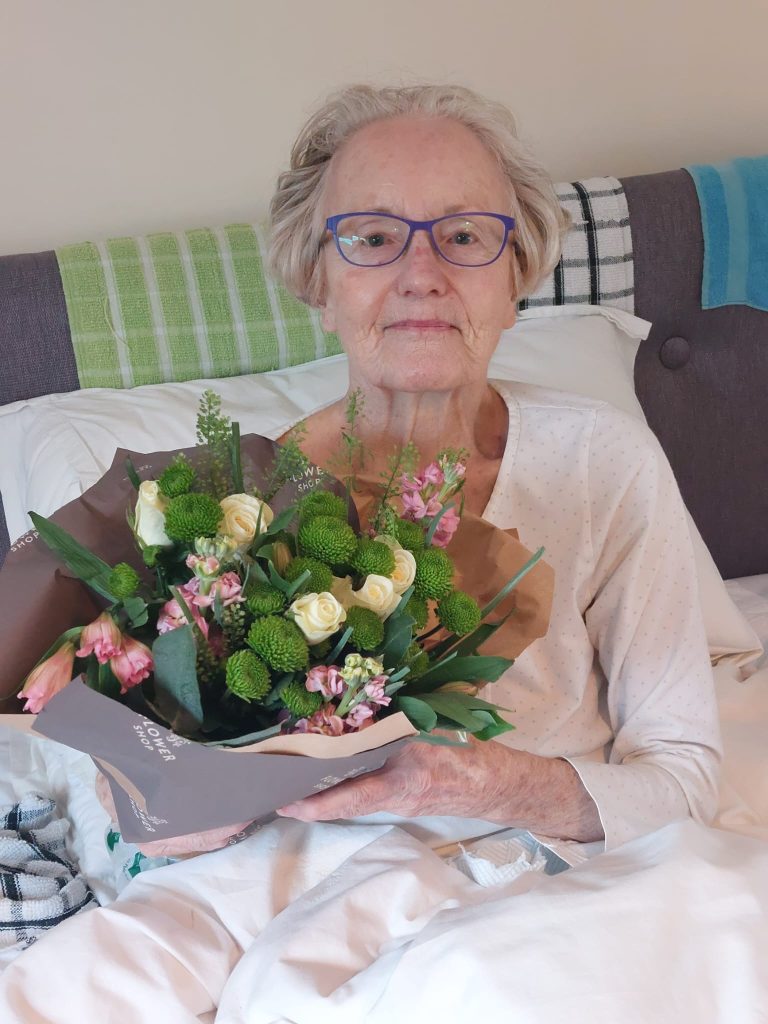 Elderly lady in bed with flowers