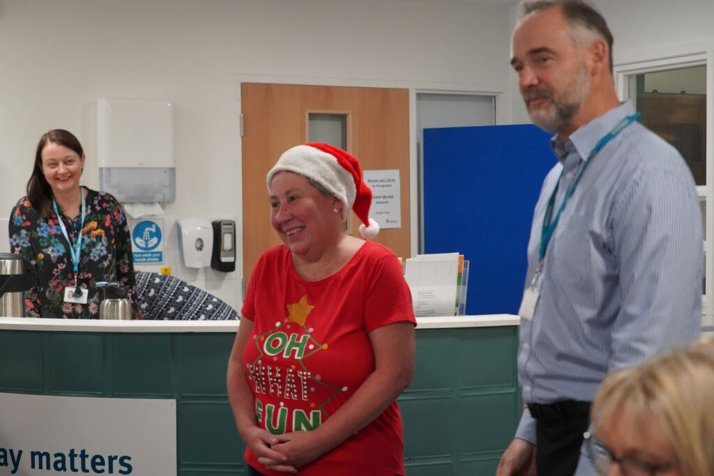 A woman dressed in a festive t-shirt and Santa hat with a man in a shirt