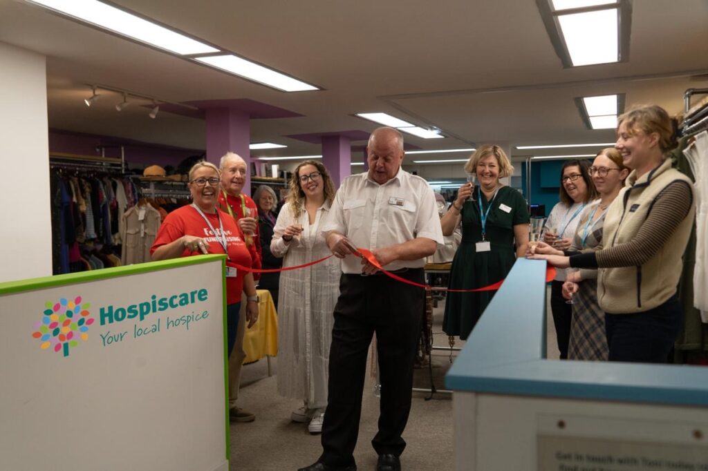 A group of people gathered around a man cutting a ribbon