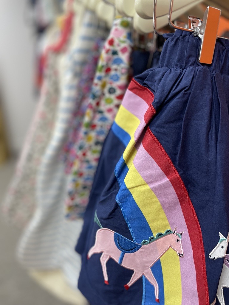 A blue skirt with a rainbow and horse at the front of a clothes rail