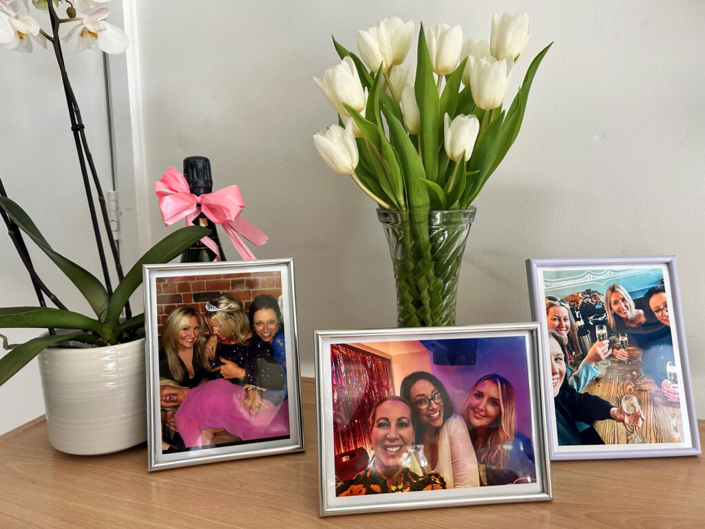 Framed photographs of women at social occasions set on a table with tulips and an orchid