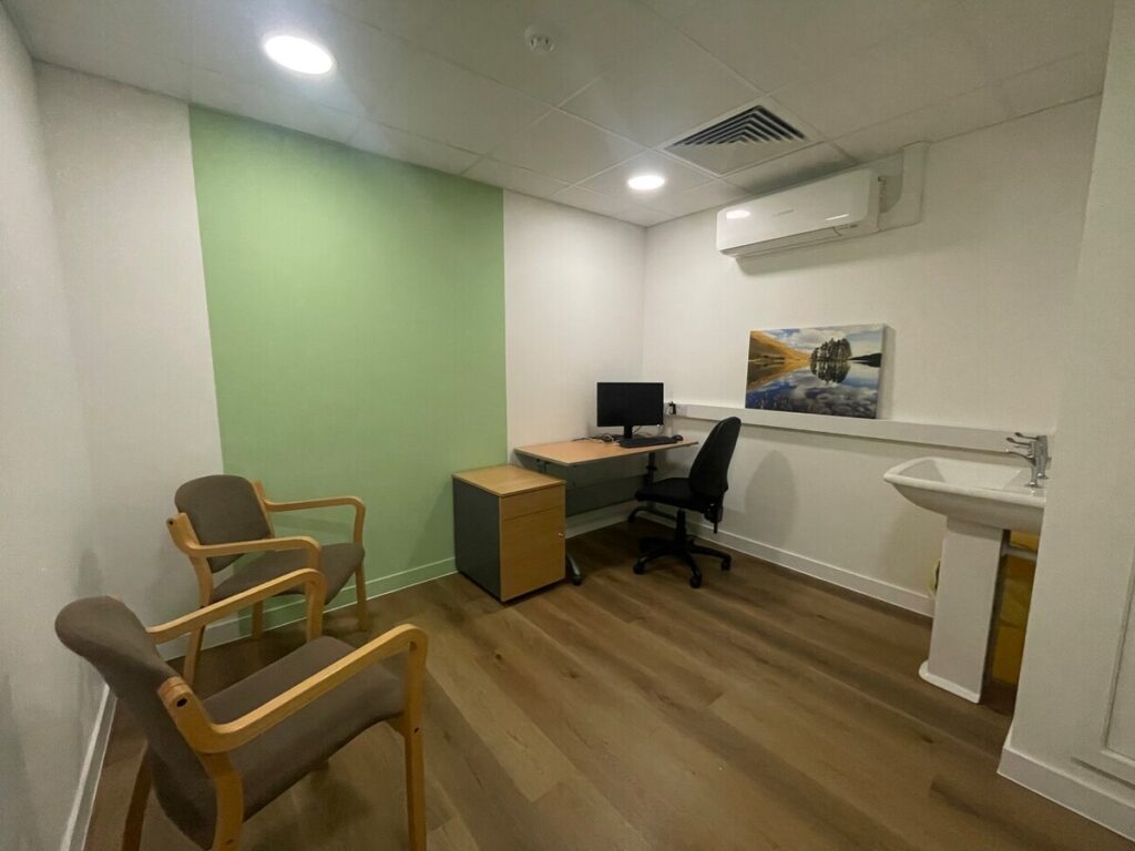 A room with chairs, a desk and a green painted panel on the wall