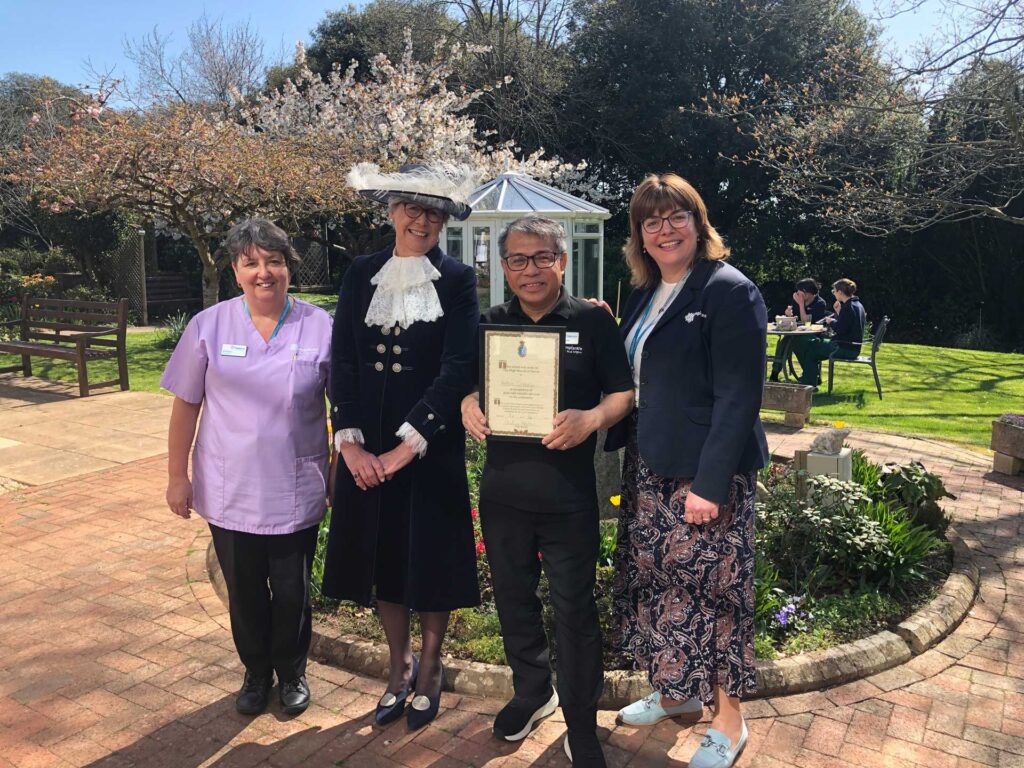 A man holding a certificate in the middle of three women in a garden
