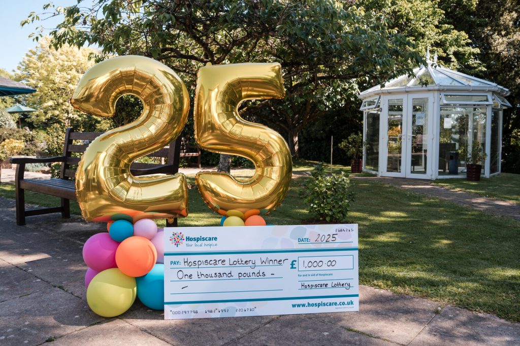Balloons showing the numbers 25 in gold behind a big cheque